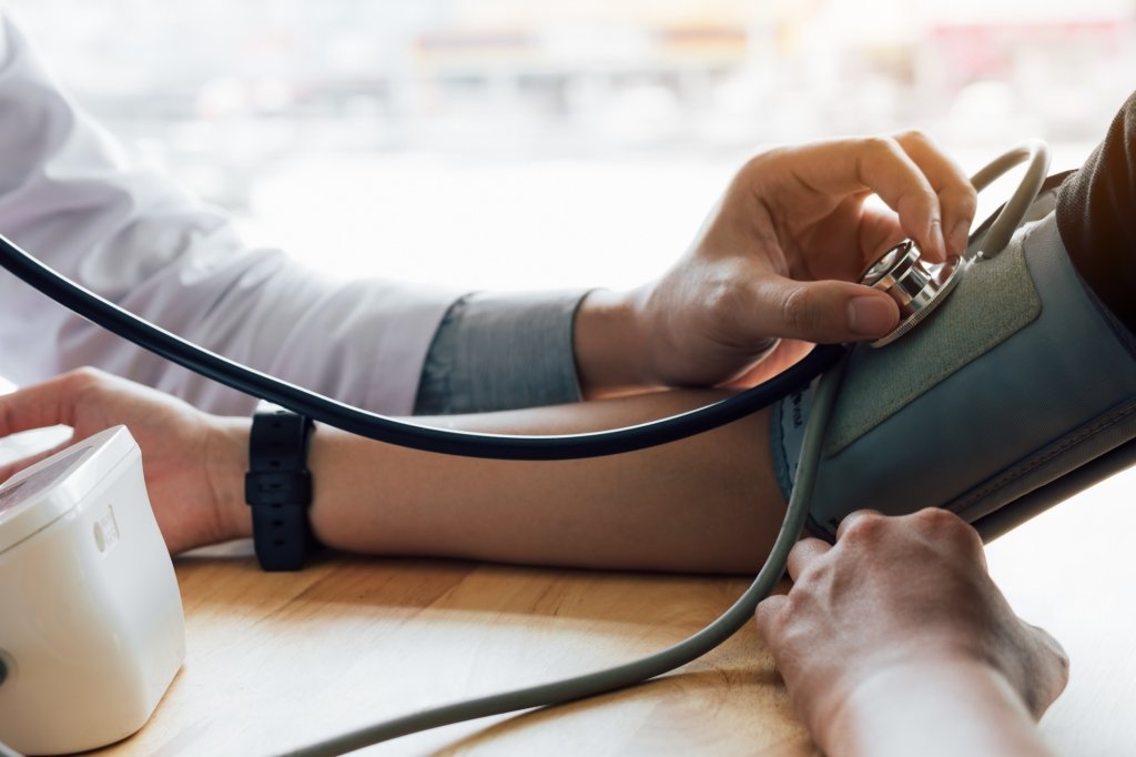 Doctor's arm with patient in hospital, taking blood pressure